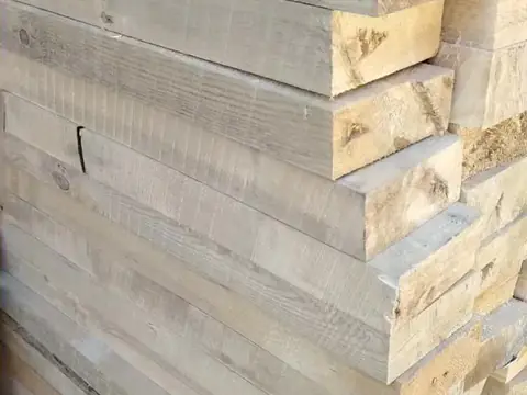 ბელორუსული ფიჭვის სქელი ფიცრებისა და ძელების დასტა ღია ცის ქვეშ.